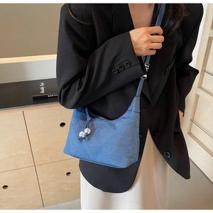 Détail du sac croissant en denim matelassé bleu clair avec perles blanches et boucle argent