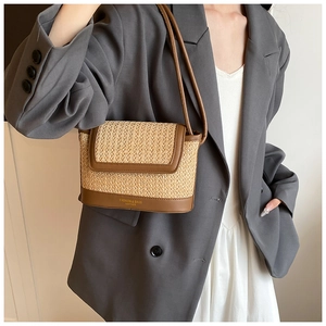 Detail of hand-woven straw shoulder bag with brown leather trim and fashion logo