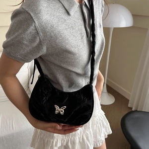 Elegant black velvet shoulder bag with silver butterfly buckle on a fashion model