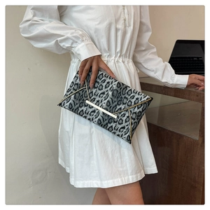 Detail of leopard print clutch featuring gold V-shaped metal trim and flap closure