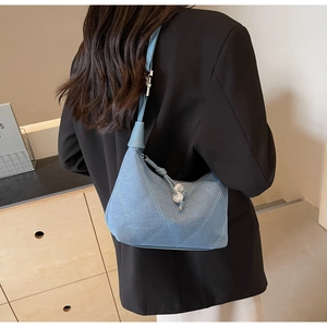 Détail du sac hobo en jean bleu clair avec surpiqûres en losanges et tirette à perles