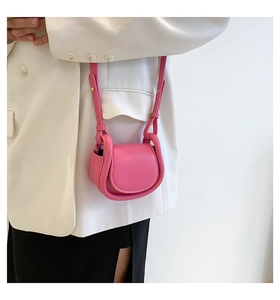 Pink mini leather crossbody bag with rounded edges and semi-circular flap on model