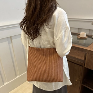 Sac fourre-tout tissé marron à texture verticale et boucle en métal porté par un mannequin