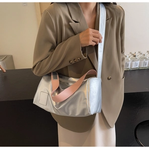 Chic silver cylinder handbag with pink wide strap worn on shoulder by a model