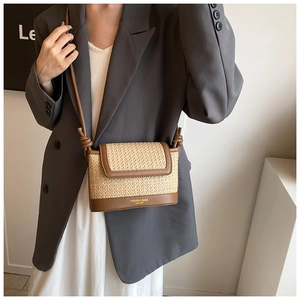 Detail of straw and leather crossbody bag with golden fashion text on neutral model