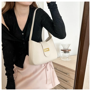 Detail of off-white leather shoulder bag with sleek gold metallic buckle closure