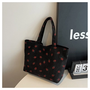 Detail of strawberry print on black corduroy tote bag with textured stripe fabric