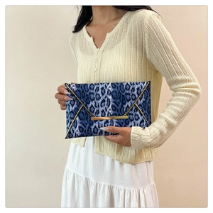 Blue leopard print envelope clutch featuring metallic gold trim detail held by model