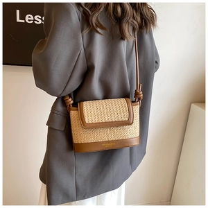 Detail of straw woven crossbody bag with brown leather trim and fashion logo