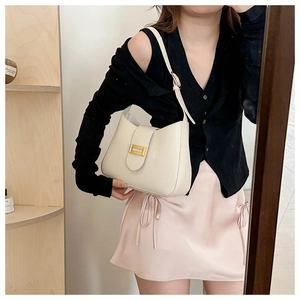 Detail of minimalist beige faux leather shoulder bag with a gold decorative buckle