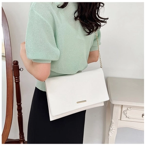 Close-up of minimalist white PU leather clutch with golden chain strap and metal trim