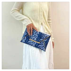Detail of blue leopard print envelope clutch with gold metal bar trim and foldover flap