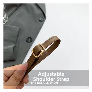 Detail of adjustable brown leather shoulder strap with a gold square metal buckle