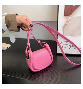 Detailed view of pink semi-circular leather mini bag with flap and adjustable strap