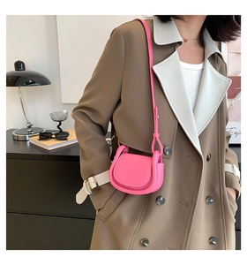 Chic rose pink saddle bag for kids worn by model in a stylish trench coat outfit