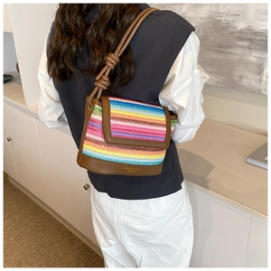 Detail of colorful rainbow woven bag with brown leather trim and knot strap detail