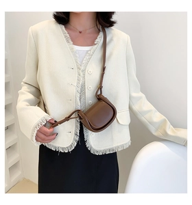 Brown mini faux leather saddle bag worn crossbody on model with chic tweed jacket