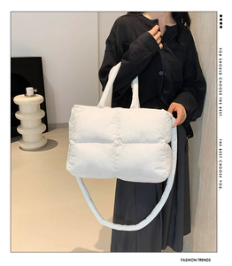 Close-up of white quilted puffer tote bag featuring soft down-filled square patterns