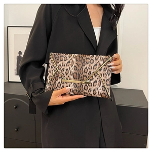 Close-up of leopard print envelope clutch with gold V-metal trim held by a model