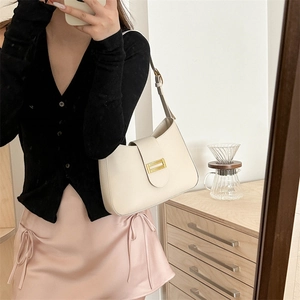 Chic cream white baguette shoulder bag with gold buckle shown on model in warm indoor setting