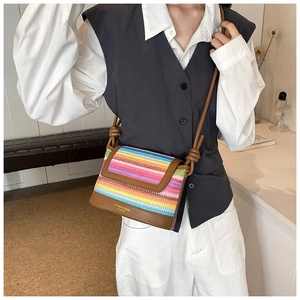 Close-up of rainbow striped woven crossbody bag with brown leather base detail