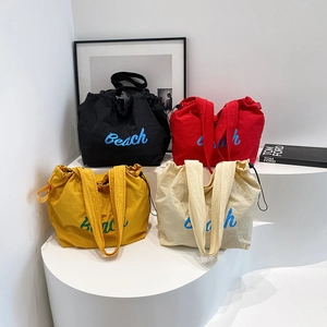 Set of four minimalist canvas tote bags in black, red, yellow, and beige with Beach embroidery