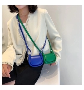 Miniature saddle crossbody bags in royal blue and bright green on model in white jacket
