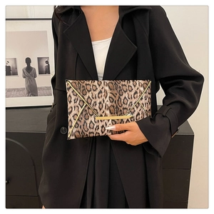 Close-up of leopard print envelope clutch with luxury gold metal trim and textured leather