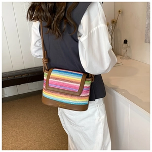 Detail view of rainbow woven crossbody bag with brown leather base and adjustable strap