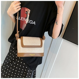 Close-up of woven straw crossbody bag with brown leather flap and fashion logo