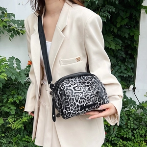 Leopard print shell crossbody bag with adjustable black strap and round canvas design