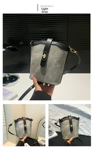 Detail view of the light grey contrast bucket bag with gold turn-lock and adjustable strap
