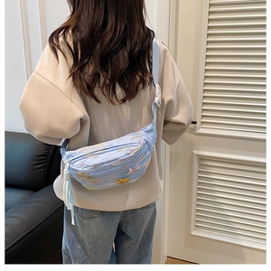 Detail of light blue crossbody bag with star embroidery and long decorative fringe