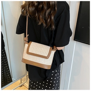 Detail of beige woven straw shoulder bag with brown leather trim and knotted strap