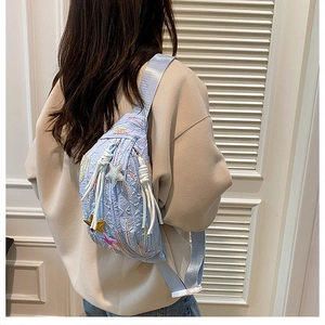 Close-up of quilted light blue chest bag with star patches and woven strap details