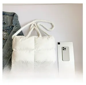 Detailed top view of white quilted puffer tote bag with laptop and denim jacket