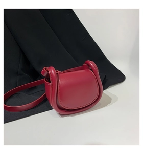 Detail of burgundy mini saddle bag with padded trim and slim leather shoulder strap