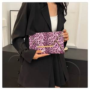 Detail of purple leopard print envelope clutch with gold metal trim held by a model