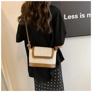 Detail of a straw crossbody bag with brown leather trim and fashion text on white wall