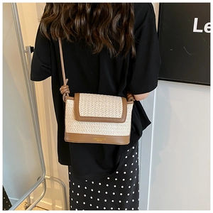 Detail of woven straw crossbody bag with brown leather trim and knotted strap detail