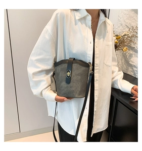 Detail of grey suede bucket bag with black leather trim and gold turn-lock closure