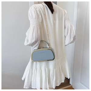 Dettaglio borsa a scatola trapezoidale celeste con catena e finiture in metallo oro