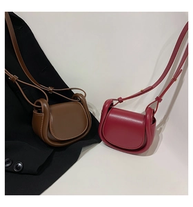 Detail of mini leather saddle bags in brown and burgundy with gold hardware