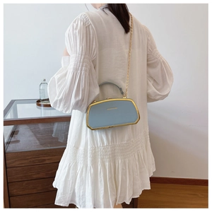 Dettaglio della borsa a trapezio blu Morandi con cornice dorata e tracolla a catena moda