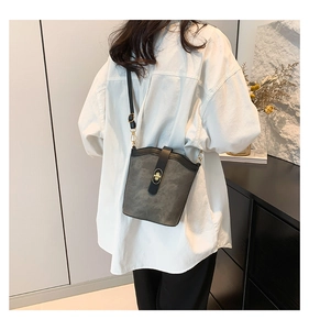 Detail of grey suede bucket bag with black leather trim and gold twist lock closure