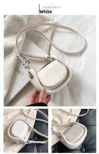 Close-up of minimalist white mini saddle bag with smooth leather finish and fine stitching