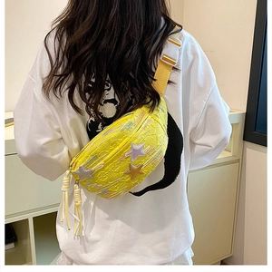 Detail of yellow fabric chest bag with star embroidery and colorful fringe tassel charms