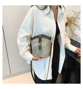 Detail of grey bucket bag showing the matte texture and gold metal turn-lock closure