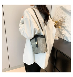 Detail of grey vintage bucket bag with black leather trim and golden turn-lock closure