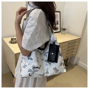 Détail d'un grand sac fourre-tout blanc à imprimé papillon avec une pochette noire